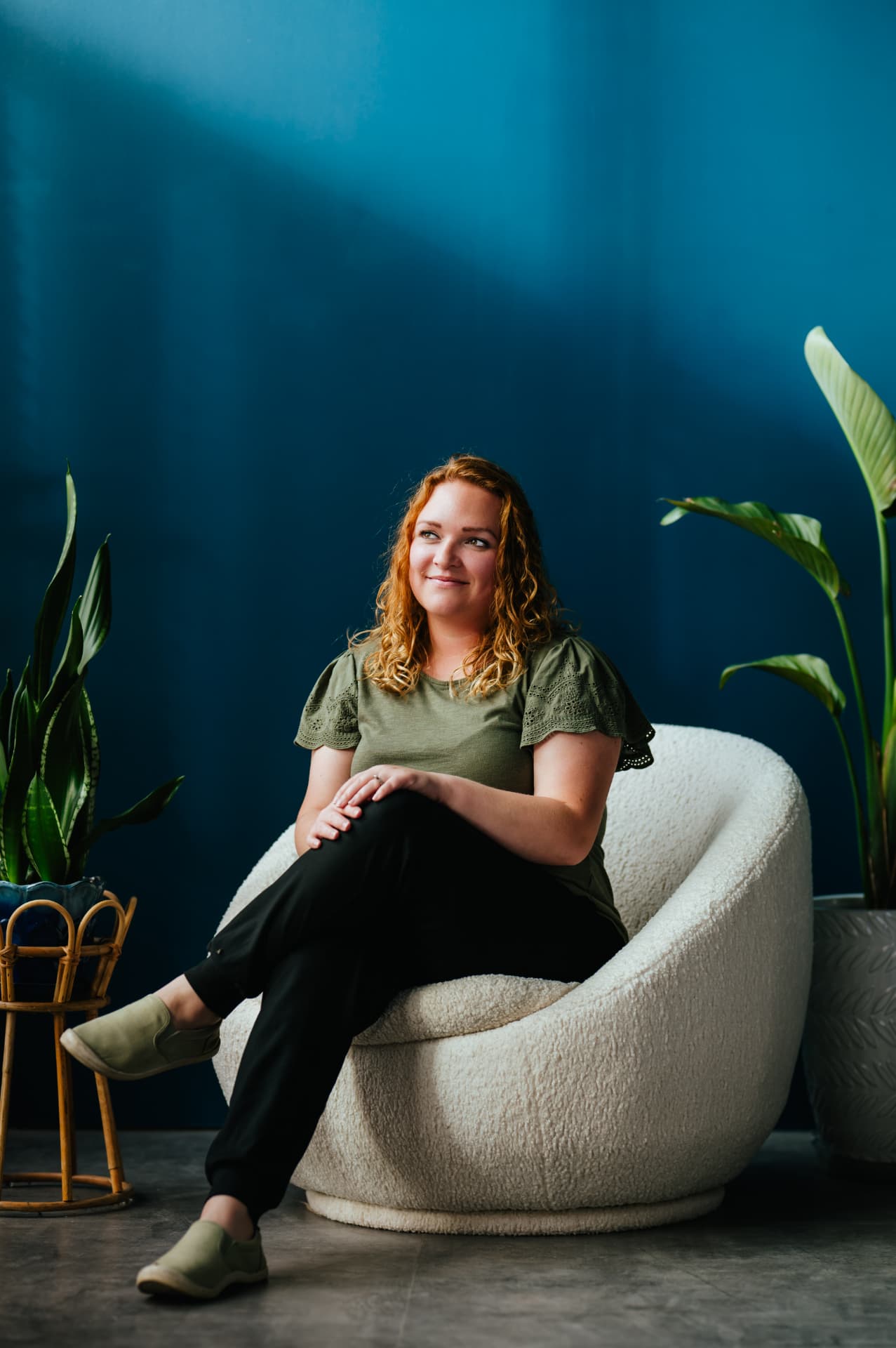 Samantha Stefaniak, LMHC, seated in a white armchair against a deep teal wall